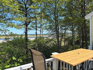 Eine Holzterrasse mit Tisch und Stühlen mit Blick auf einen Strand und den Ozean.