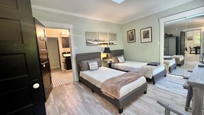 A hotel room with two beds, a bathroom, a desk, and a large mirror.