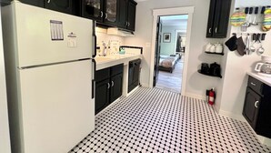 A kitchen with black cabinets, a white refrigerator, and a patterned floor.