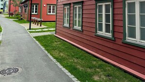 A red building with multiple windows and a paved walkway. - TotalApartments - Vervet Studio Apartments (Tromsø)