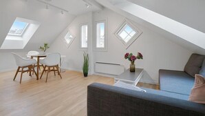 A modern loft apartment with a dining area, a sofa, and a small table with flowers. - TotalApartments - Vervet Studio Apartments (Tromsø)