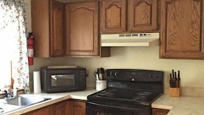 A kitchen with wooden cabinets, a stove, a microwave, and a sink. - Ogunquit -2 Bedroom Family Condo with POOL 2 week stay (Ogunquit)