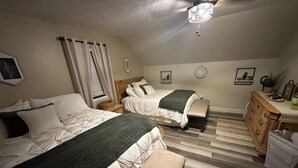 Une chambre avec deux lits, une commode et un ventilateur de plafond.
