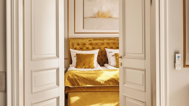 Een slaapkamer met een bed, een deur en een plafondlamp.