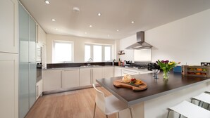 A modern kitchen with a central island, stainless steel appliances, and a large window. - Dog friendly, two bedroom holiday apartment with balcony in Mortehoe, North Devon. (Mortehoe)