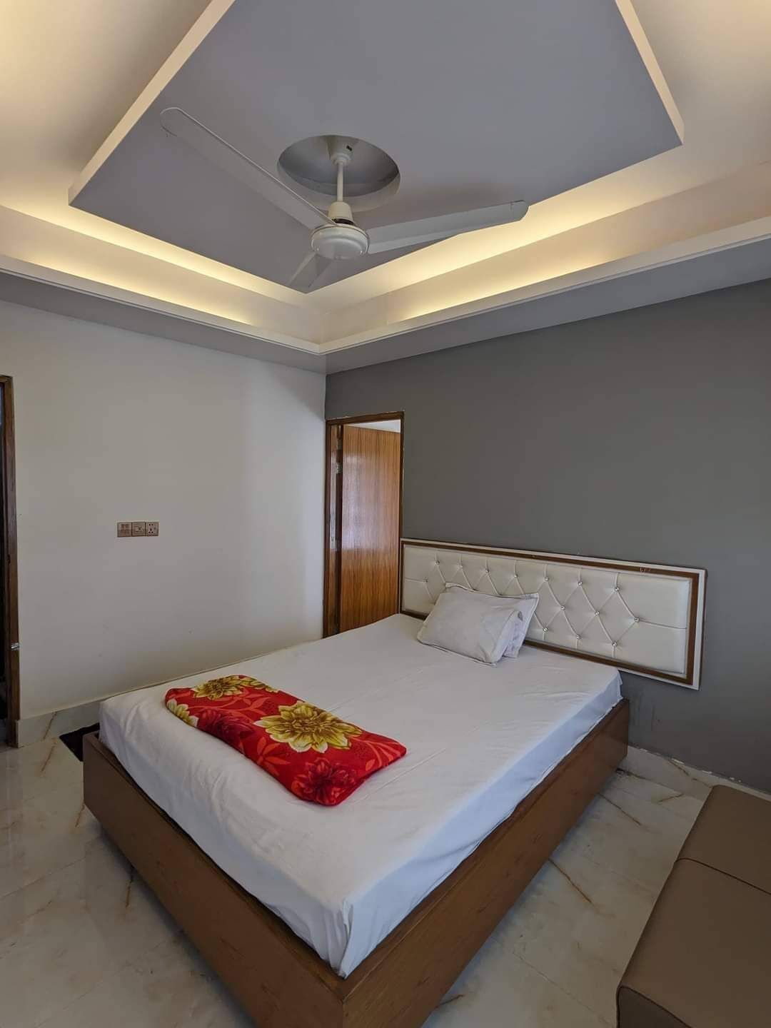 A modern bedroom with a large bed, a ceiling fan, and recessed lighting.