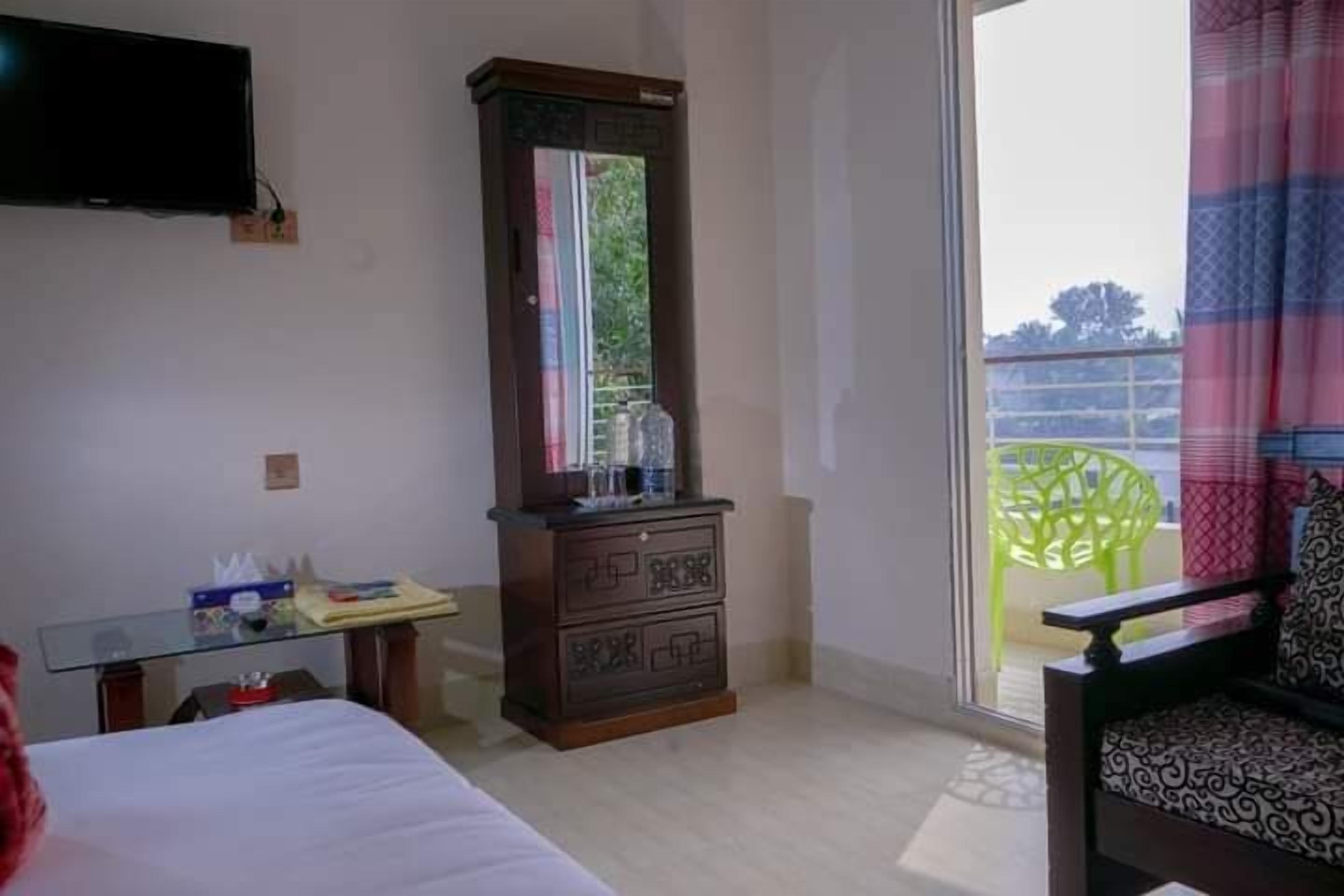 Hotelkamer met een bed, een dressoir, een aan de muur bevestigde televisie en uitzicht op het balkon.