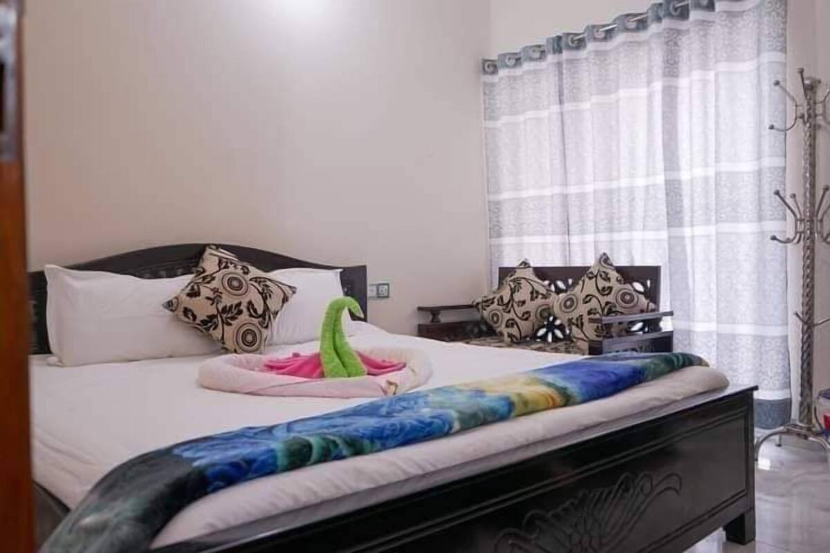 A neatly made bed with patterned pillows, a decorative pillow, and a colorful blanket.