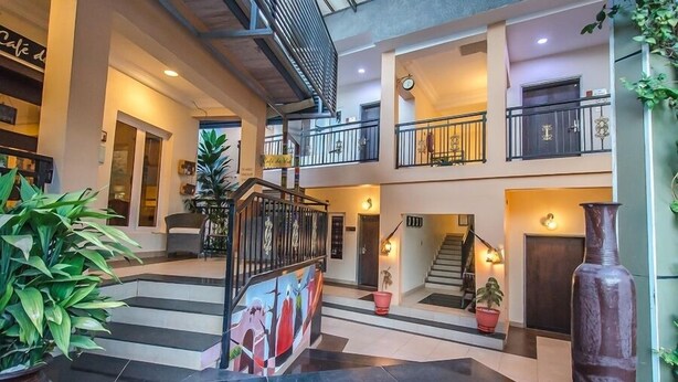 Un intérieur à plusieurs niveaux, avec un escalier central, des plantes en pot et une fresque murale.
