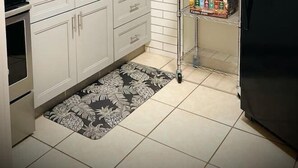 Cocina compacta con alacenas blancas, un refrigerador negro, microondas y cafetera sobre la encimera.