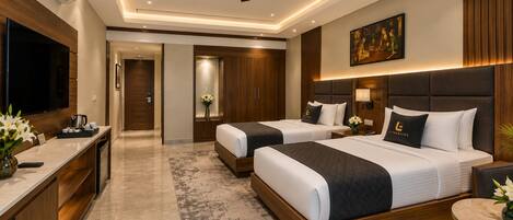 A hotel room with two beds, a TV, a desk, and a ceiling fan.