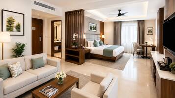 A hotel room with a sofa, a coffee table, a bed, a desk, and a TV.
