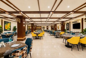 Uma sala de jantar ampla com várias mesas e cadeiras, piso polido e design moderno no teto.