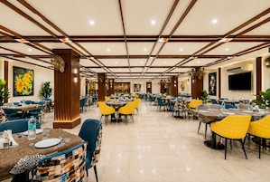 Un'ampia sala da pranzo con diversi tavoli e sedie, un pavimento lucido e un design moderno del soffitto.