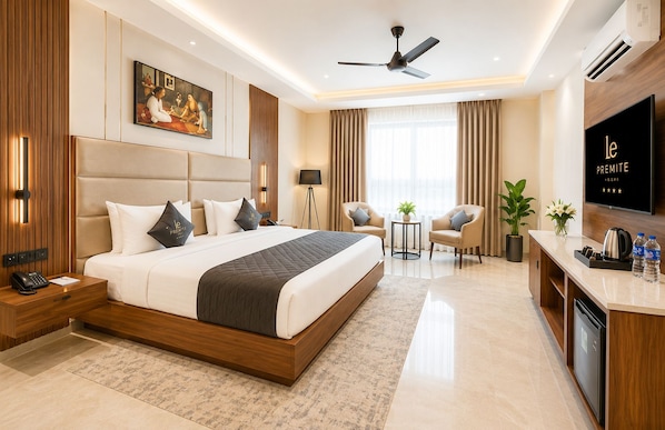 Habitación de hotel con una cama grande, un escritorio, un televisor de pantalla plana, un ventilador de techo y una ventana con cortinas.