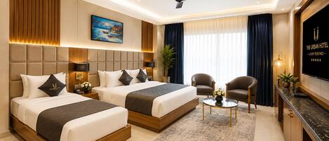 A hotel room with two beds, a ceiling fan, a TV, a desk, and a chair.