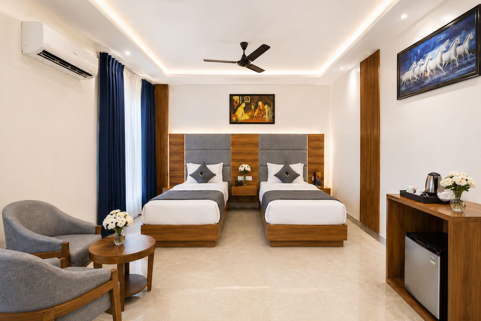 A hotel room with two beds, a desk, a chair, and a ceiling fan.