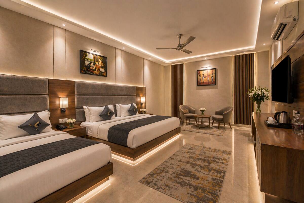 A hotel room with two beds, a desk, a chair, a TV, and artwork on the walls.