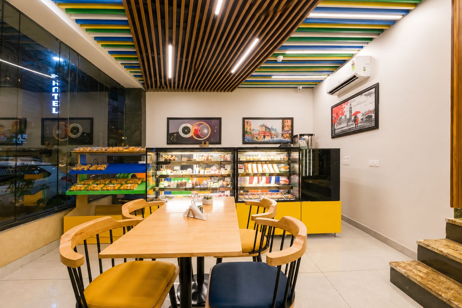 A café with a wooden table, chairs, and a display case with pastries.