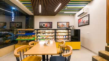 A café with a wooden table, chairs, and a display case with pastries.