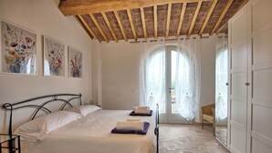 A bedroom with a bed, a wooden ceiling, a door, and a window with curtains.