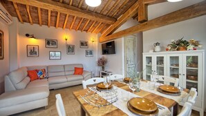 A cozy living room with a sofa, dining table set with plates, and a cabinet with glass doors.