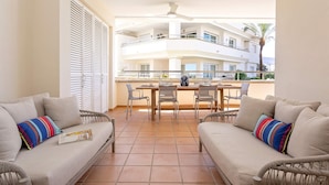 Ein Balkon mit zwei Sofas, einem Esstisch und Stühlen.