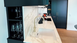 A modern kitchen with a marble countertop, a gold faucet, and dark cabinetry. - Beautiful apartment in historic Wangen im Allgäu (Wangen im Allgäu)