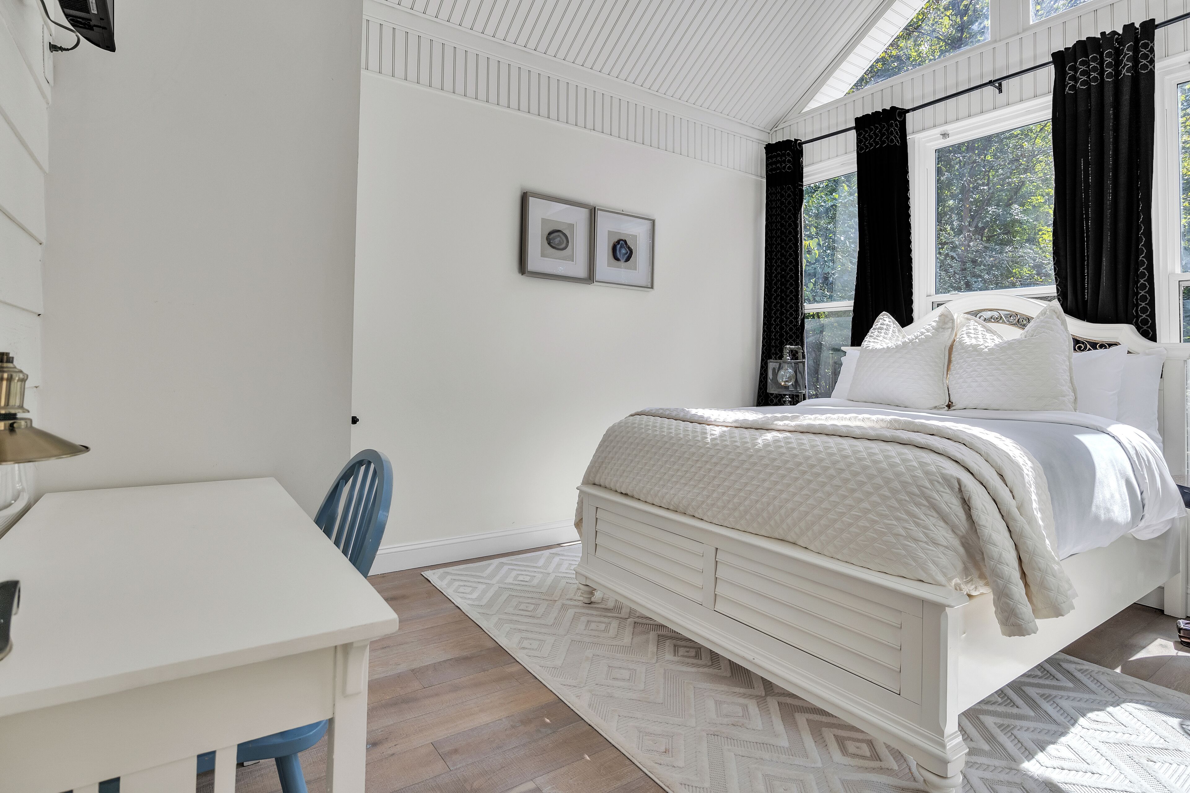 A bedroom with a bed, a desk, and a chair.