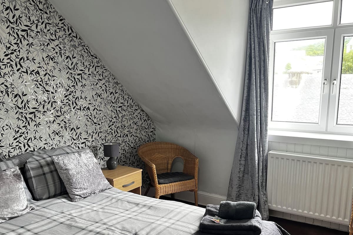 Une chambre à coucher avec un lit, une chaise, une fenêtre et un radiateur.