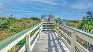 A wooden boardwalk leading to a gate, surrounded by greenery. - Charming 1-bedroom condo in welcoming Isle of Palms with AC, WiFi (Isle of Palms)