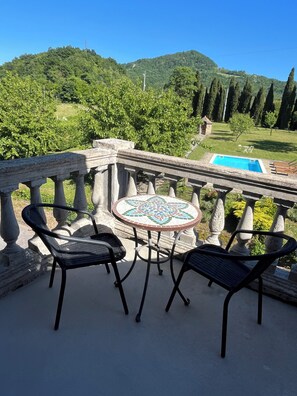 Un balcon avec vue sur une piscine et des collines.