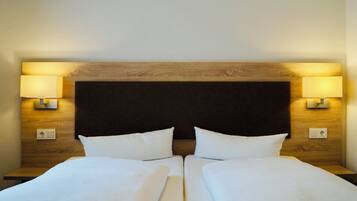 Ein Doppelbett mit Holz Kopfteil, zwei Nachttischlampen und einem Lichtschalter an der Wand.