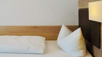 A hotel room with a wooden headboard, two white pillows, and a bedside lamp.