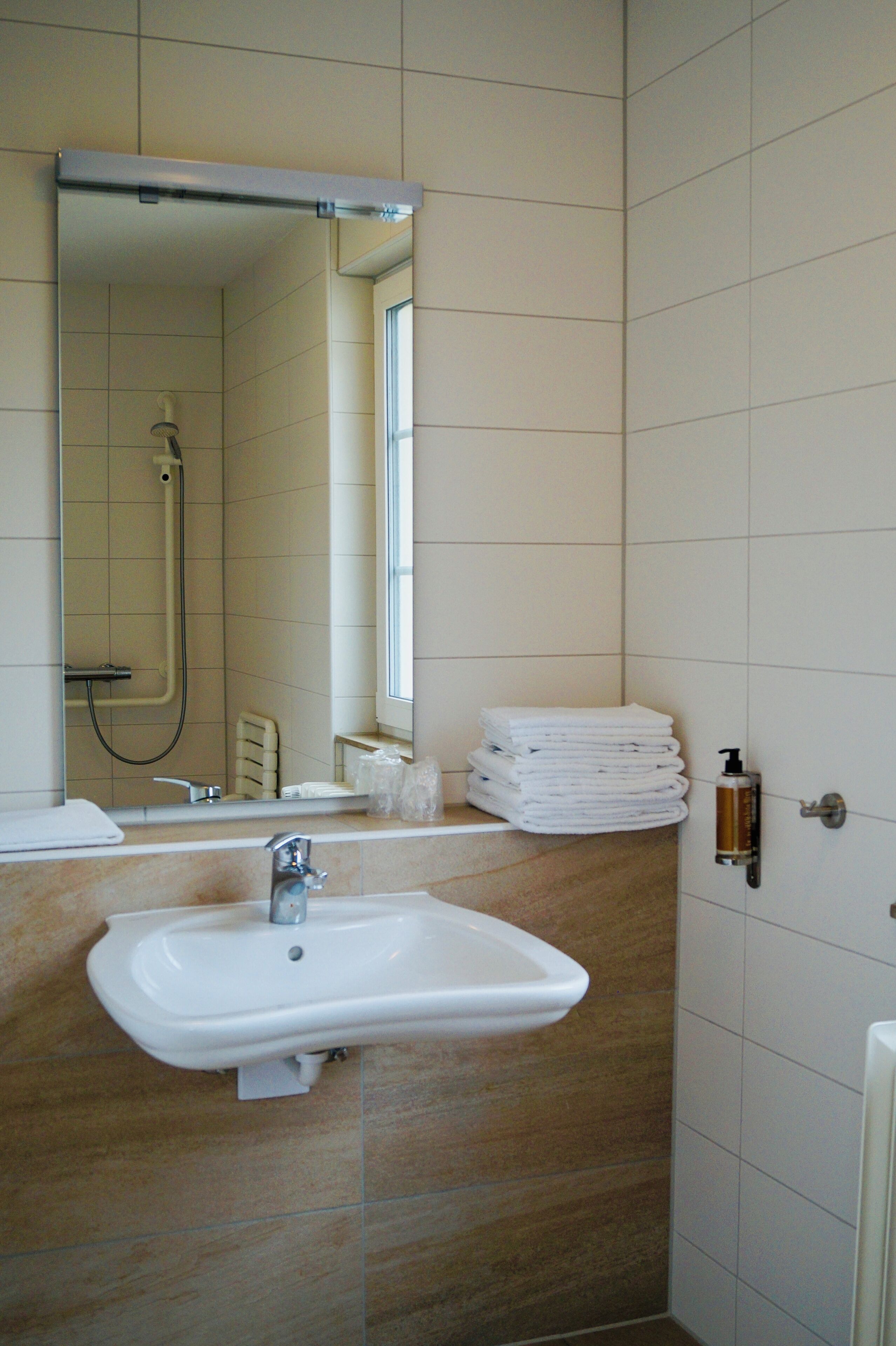 Ein Badezimmer mit Waschbecken, Spiegel und Dusche.