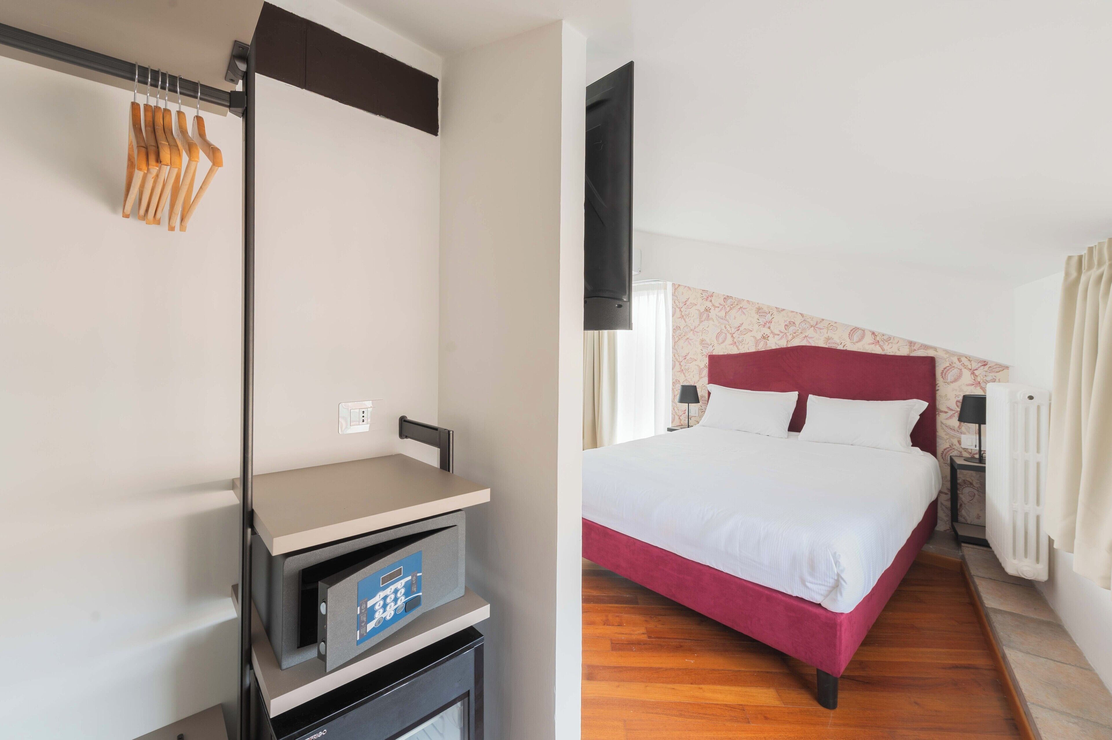 A hotel room with a bed, a desk with a chair, and a wardrobe.