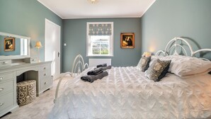 Een slaapkamer met een bed, een kaptafel, een dressoir en een kroonluchter.