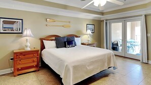 A bedroom with a bed, nightstands, a ceiling fan, and a sliding glass door leading to a balcony.