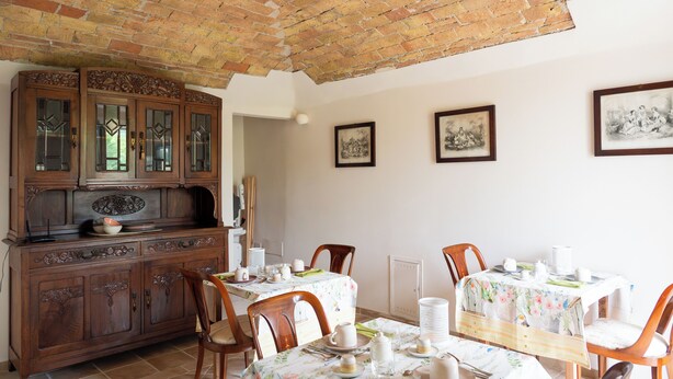 A dining area with a brick ceiling, wooden cabinets, and a table set for four.