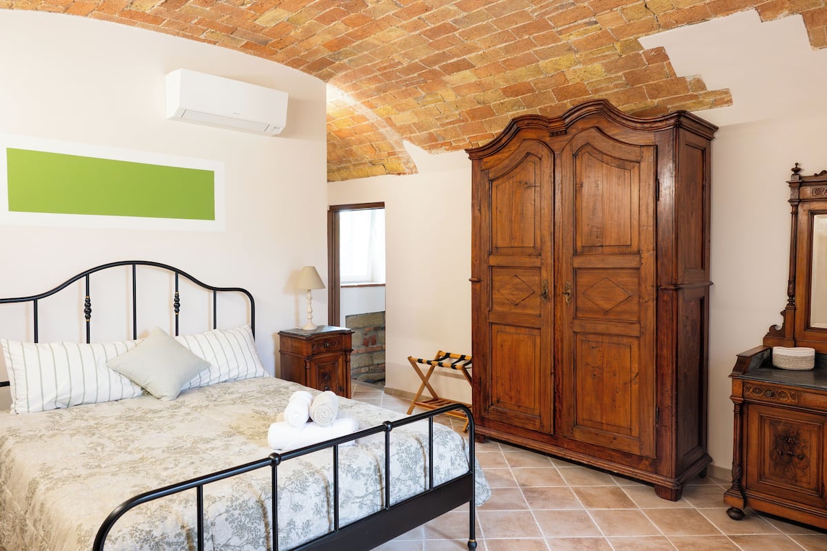 A bedroom with a bed, wooden wardrobe, and a green wall.