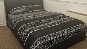 Un lit avec une tête de lit gris foncé et une couvre-lit à motifs noir et blanc.