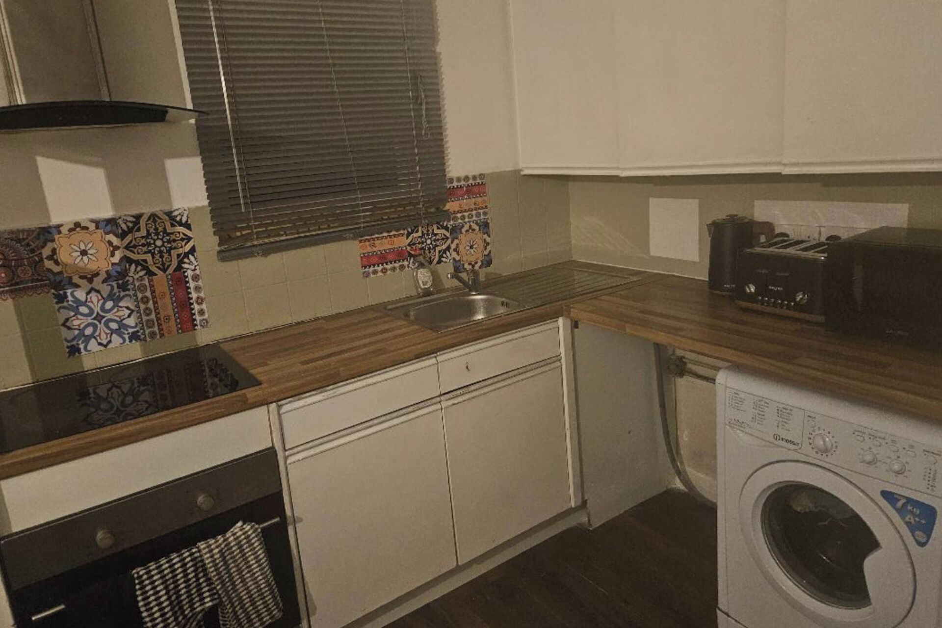 A compact kitchen with a sink, a toaster, and a washing machine.