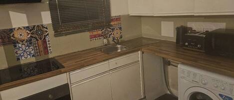 A compact kitchen with a sink, a toaster, and a washing machine.