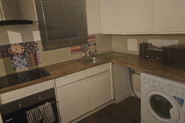 A compact kitchen with a sink, a toaster, and a washing machine. - 1 Bed House Sleeps 2 -free Parking -Tv (Romford)
