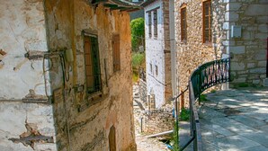 Une ruelle étroite pavée, bordée de bâtiments en pierre dotés de portes et de fenêtres en arc de cercle.