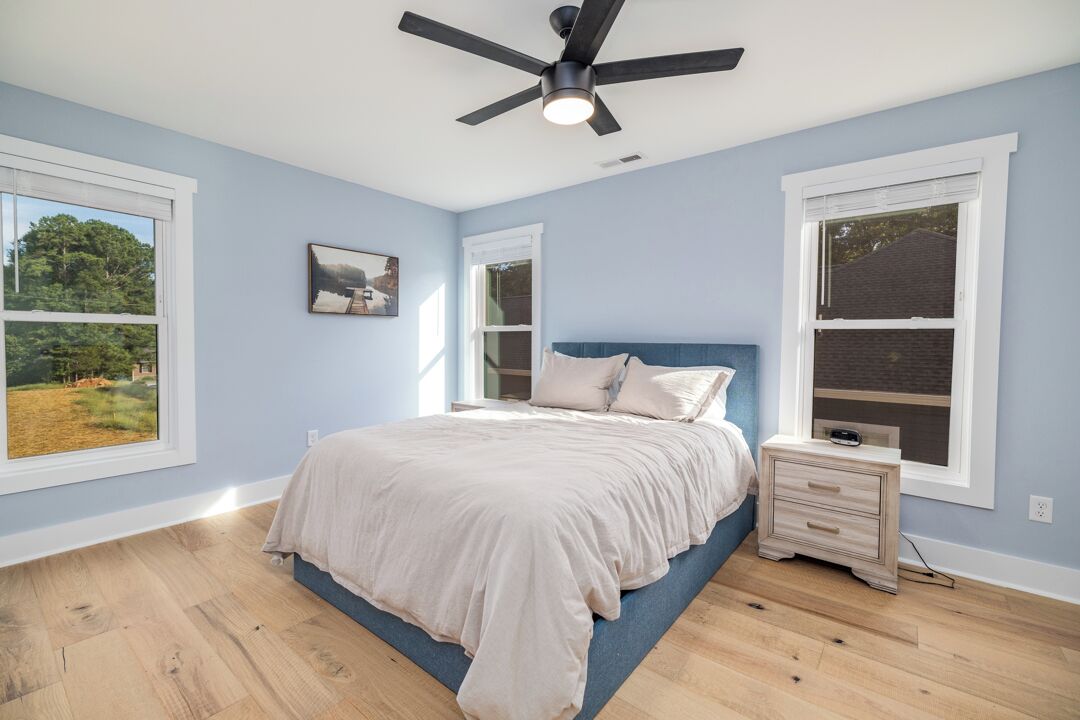 A bedroom with a bed, nightstand, and ceiling fan.