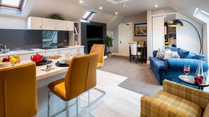 A modern kitchen with a dining area, a blue sofa, and a small table with wine glasses. - Killarney Centre Home comprising 4 separate Apartments (Sleeps 18) (Killarney)