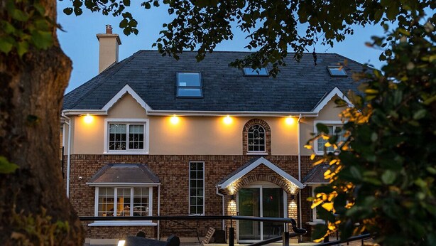 A two-story building with a brick facade, multiple windows, and a small porch area with a bench. - Killarney Centre Home comprising 4 separate Apartments (Sleeps 18) (Killarney)