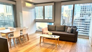 A modern living room with a sofa, coffee table, and dining area.