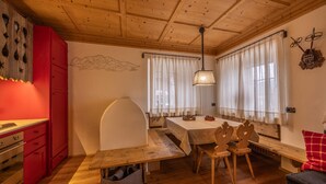 A cozy dining area with a wooden table and chairs, a bench, and a red cabinet. - Casa dell'Alpinista in Cortina d'Ampezzo (Cortina d´Ampezzo)